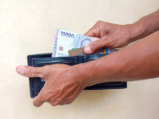 hand holding rupiah money in wallet