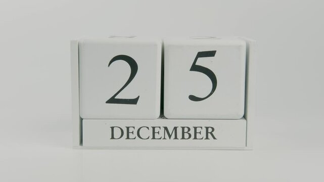 A hand flips a wooden calendar, changing the date from December 25th to December 26th, moving past Christmas Day into the final week of the year