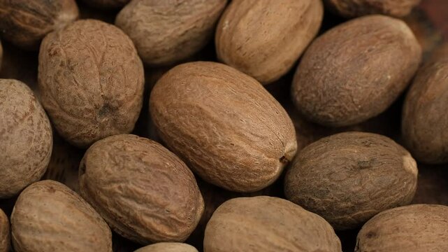 Heap of spice dried nutmeg close up, rotation