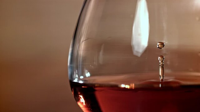 A drop falls into a glass of cognac. Filmed on a high-speed camera at 1000 fps. High quality FullHD footage