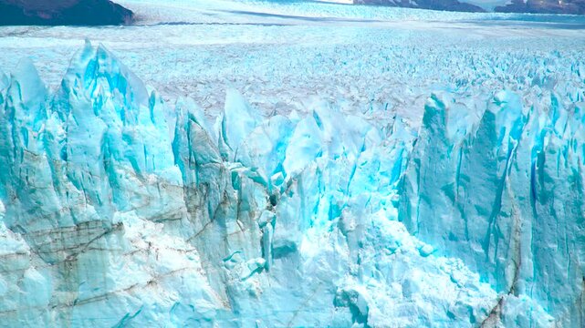 Perito Moreno Glacier in Argentina features massive blue ice formations calving into the lake below, surrounded by rocky terrain.