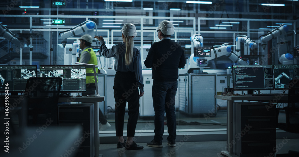 Fototapete Male Engineer and Female Project Manager Standing Next to an Assembly Line, Talking, Using Laptop and Monitoring Production at a Modern Automated Electronics Manufacture with Robotic Arms. Back View