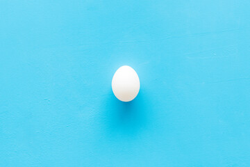 One chicken eggs on blue background, top view. Food pattern. Easter background
