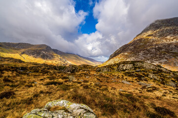 Cwm Idwal’s heather-clad corrie basin framed by rugged granite crags beneath a shifting cloudscape
