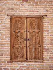 Wooden door.Vintage style wooden door with handicraft arabic pattern on the door on brick wall background,  common scene in Buchara, Uzbekistan.
