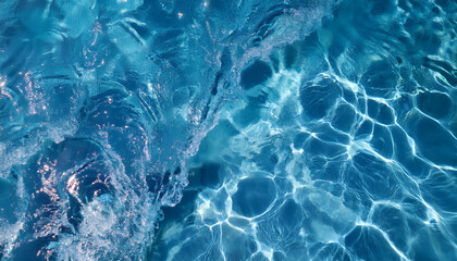 Fototapeta premium Water texture, background. Clear blue water ripples with sunlight reflections creating intricate light patterns. A splash on the left adds texture and dynamic movement