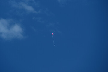 Pink balloon flying in the blue sky with white clouds on a sunny day