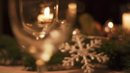 Elegant holiday ambiance with flickering candles and pine branches in soft focus