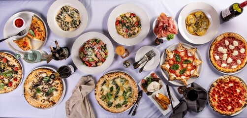 Big dinner table with italian food, pizzas and pastas, appetizers and wine, banner size
