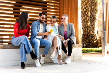 Fototapeta premium Group of diverse friends sharing a moment of connection while using a smartphone outdoors