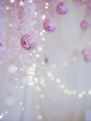Pink Decoration Ball. White room decorated in pink birthday party theme including glitter balls, flowers and small light bulbs on the background. Birthday party for little girl.