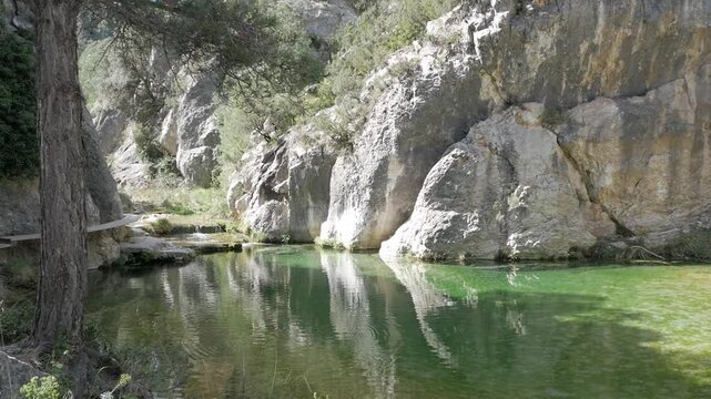 Tranquil green pool under rocky cliffs in Parrizal de Beceite, Teruel, Spain