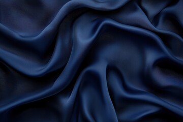Fototapeta premium Deep navy blue silk fabric, draped in flowing, wavy folds. Close-up texture shows smooth, luxurious surface
