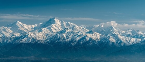 Snow-capped mountains rise majestically against a clear blue sky, their peaks etched sharply above the serene landscape.