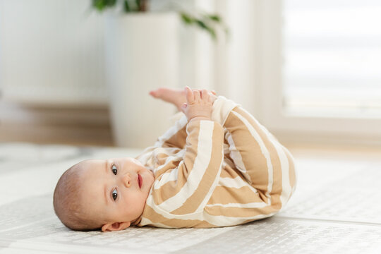 A 5 month old baby girl smiling, laying on play mat. Copy space.