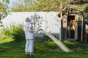 woman is watering plants with garden hose