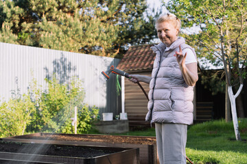 Fototapeta premium woman is watering plants with garden hose