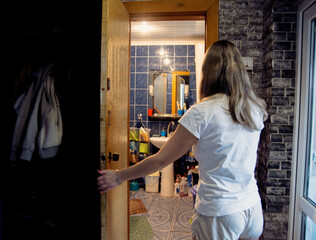A Glimpse into the Tiled Bathroom A Woman Opens the Door and Stands in the Threshold