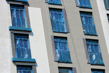 Construction Site with Polyethylene Covering Windows of Multi-Story Building