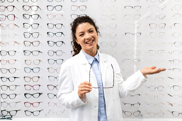 Experienced female optician showing fashionable eyeglasses for sale.