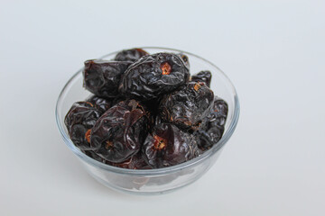 Ajwa dates or ajwa khajur, in transparent bowl, isolated on white background