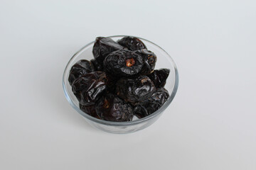 Ajwa dates or ajwa khajur, in transparent bowl, isolated on white background