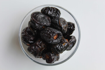 Ajwa dates or ajwa khajur, in transparent bowl, isolated on white background, flat lay or top view
