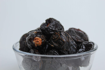 Ajwa dates or ajwa khajur, in transparent bowl, isolated on white background