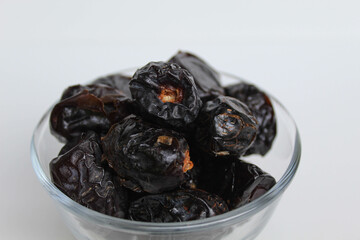 Ajwa dates or ajwa khajur, in transparent bowl, isolated on white background