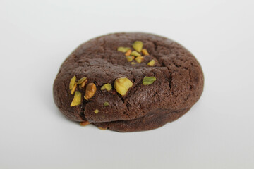 A chocolate soft cookie, with green pistachio topping, isolated on white background