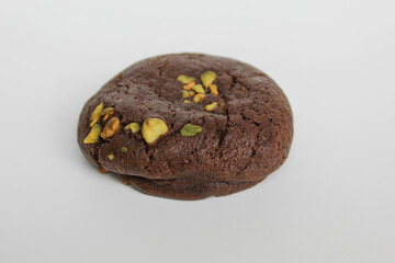 A chocolate soft cookie, with green pistachio topping, isolated on white background