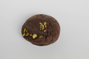 A chocolate soft cookie, with green pistachio topping, isolated on white background