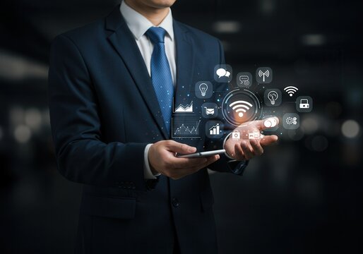 Businessman holding smartphone with digital icons hovering above his hands in a dark setting
