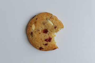 A bitten white choco soft cookie with almond and berry cuts, isolated on white background