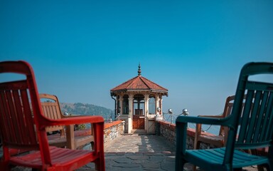 summer ,Shimla, Himachal Pradesh ,india Colorful chairs atop a mountaintop gazebo