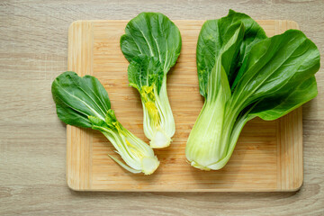 Cut green pak choi cabbage leaves on wooden board. Fresh chinese cabbage pak choi on wooden board. top view.