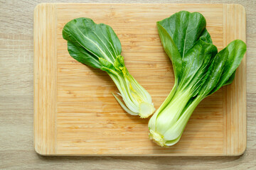 Cut green pak choi cabbage leaves on wooden board. Fresh chinese cabbage pak choi on wooden board. top view.