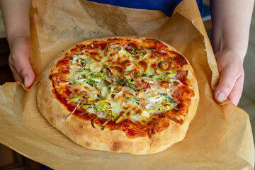 Fresh homemade pizza in the hands of the cook. Top view
