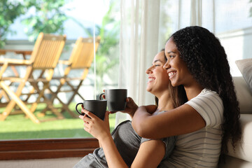 Happy interracial lesbian couple drinking and contemplating
