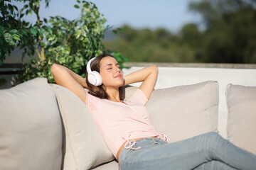 Fototapeta premium Happy woman relaxing listening audio with headphone outside