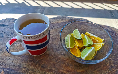 Cup with ginger tea and lemon orange lime citrus fruits.