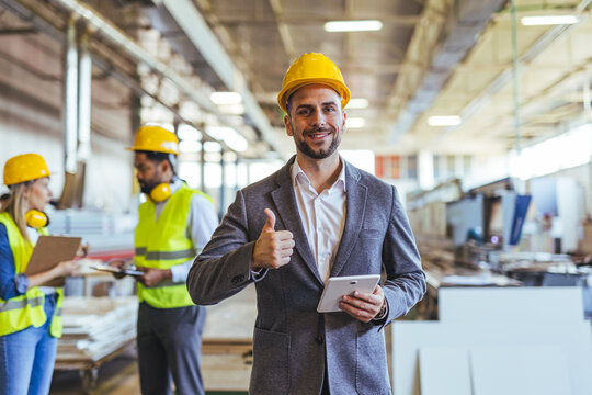 Confident Manager in Factory Settings Giving Thumbs Up Wearing Safety Helmet