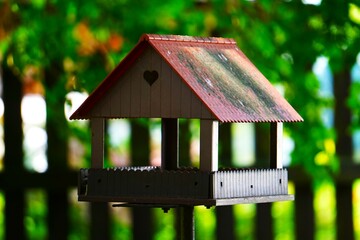 Uroczy domek dla ptaków wykonany z drewna. Czerwony daszek i widoczne serce z przodu. © Adam