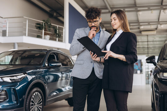 Car dealer showing automobile features to potential customer