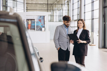 Car dealer showing vehicle model specifications to customer in a showroom