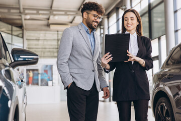 Car dealer showing vehicles to customer in a showroom