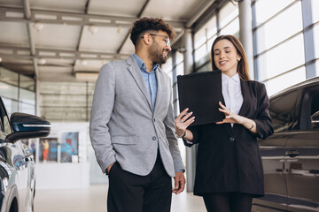 Car salesperson showing new vehicle to customer in dealership