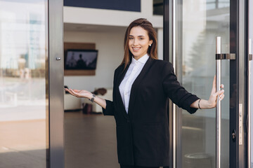 Saleswoman inviting customers inside new car dealership