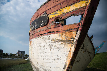 An abandoned wooden boat resting on the estuary bank at Le Crotoy, France, with weathered wood and rotting hull, captured in a serene, coastal landscape.
