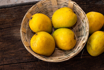 Ripe mango tropical fruit in basket on wooden table at mangoes farm